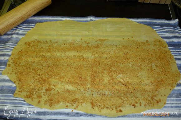 От одной из длинных сторон отступим 7 см, остальное тесто посыпаем растолченным в крошку печеньем.