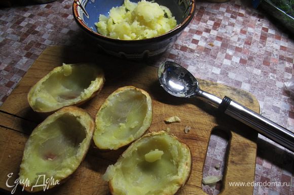 Когда картофель испечется, немного охладить его, вынуть из фольги. Аккуратно, ложкой извлечь мякоть, переложить в мисочку и смешать со сметаной и половиной сыра.