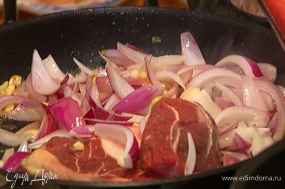 В сковороду с мясом добавить лук и чеснок и готовить, пока они не зазолотятся.