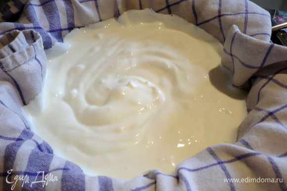 Перемешиваем йогурт с солью, ставим сито на кастрюлю, выкладываем его в два слоя хлопчато-бумажным полотенцем так, чтобы края полотенца свисали с сита, и выливаем в сито йогурт.
