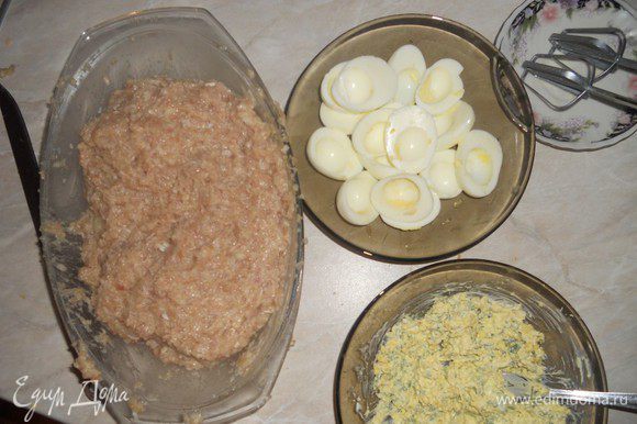 Приготовить фарш. Добавить свежее яйцо, замоченную в молоке мякоть хлеба, соль, перец. Хорошенько перемешать. Варeные яйца почистить и разрезать пополам. Вынуть желток. Натереть на мелкой тeрке сыр и порезать мелко зелень. Смешать с майонезом и желтками. Начинить этой смесью белки от яиц. Соединить между собой две половинки яиц. Фарш разделить на пять разных частей. Из каждой части сформировать лепeшку, положить на середину фаршированное яйцо, слепить овал. С одной стороны вытянуть носик eжика (поднять вверх).
