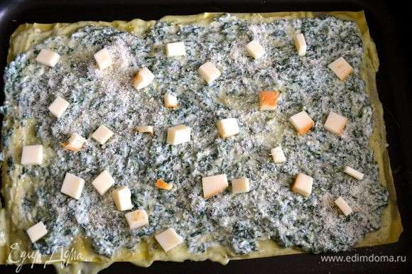 Сверху распределяем крем на рикотте со шпинатом. Присыпаем тертым сыром пармезан и выкладываем кубики копченого сыра.
