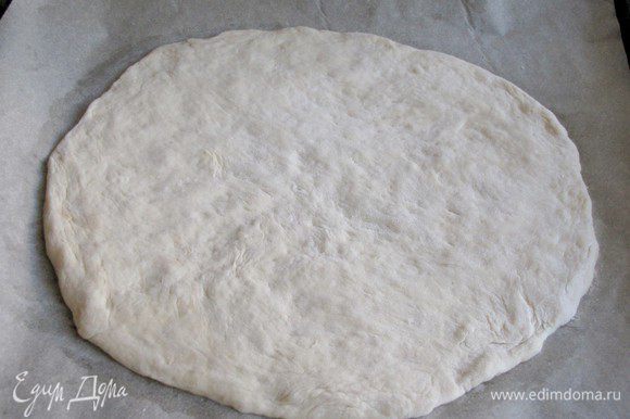 Когда тесто подойдет, разделить его на две части. Каждую часть раскатать в круг, толщиной 0,5 см. Выложить на противень, застеленный пекарской бумагой.