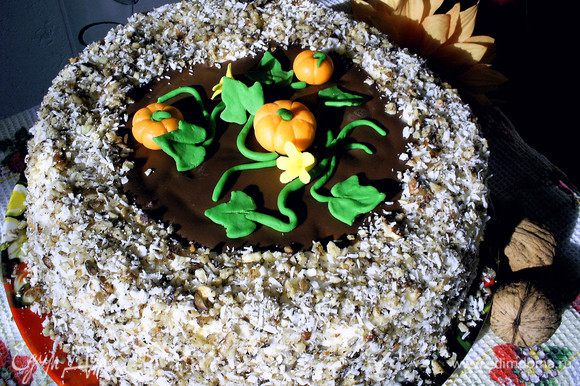 На средину торта выкладываем застывший шоколадный диск. Сверху выкладываем тыковки, цветочки и листву, формируя кустик. Оставшееся пространство засыпаем посыпкой. Отправляем торт на несколько часов в холодильник. Приятного аппетита!