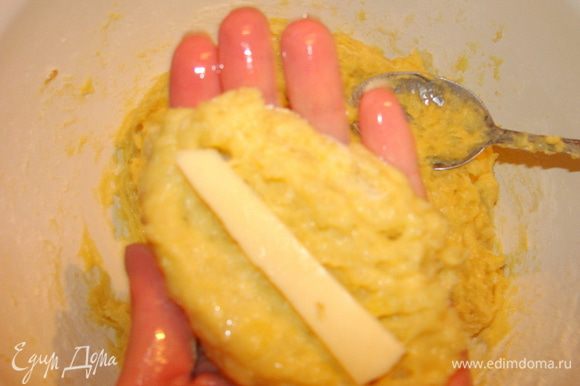 Смазать руки растительным маслом, чтобы тесто не прилипало. Столовой ложкой отщипнуть кусочек теста. Внутрь погрузить брусочек сыра.