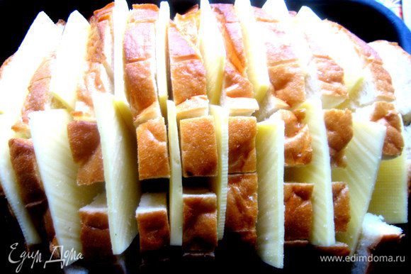 Помещаем хлеб в смазанную форму,раздвигаем слегка куски и всовываем по два кусочка сыра между ломтями.