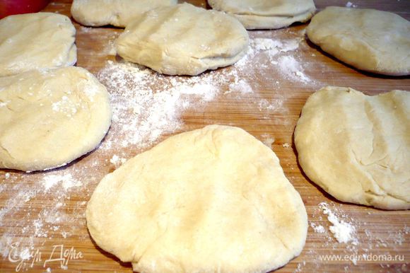 На хорошо присыпанной мукой поверхности скатываем тесто в багет и делим его на 9 равных частей, каждую часть немного разминаем руками в лепешку.