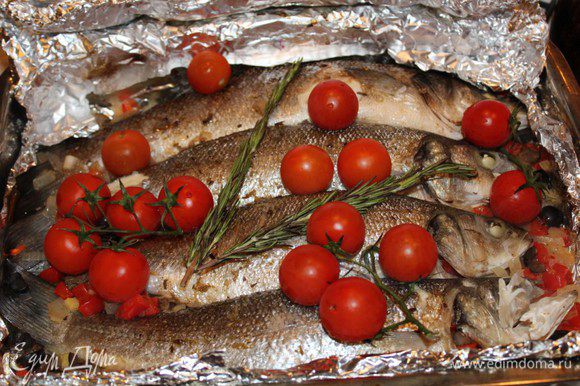 Запечь рыбу в разогретой до 200 градусов духовке в течение 15 минут. Затем достать, выложить на рыбу веточку розмарина и помидоры. Запекать еще 10 минут.