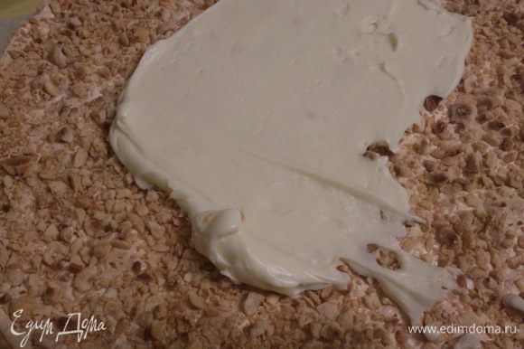 Кладем половинку бисквитного коржа, промазываем его сметанным кремом. Сверху кладем рубленый корж белками вверх, смазываем половиной масляного крема.