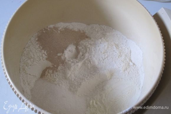 В просеянную муку добавить сахар, соль, сухие дрожжи, сухое молоко.