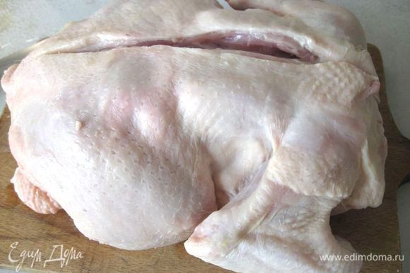 Положить курицу на доску грудкой вниз, надрезать по хребту.