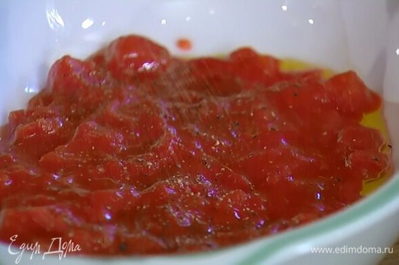 В керамическую жаропрочную форму выложить томаты в собственном соку, посолить, поперчить и сбрызнуть оливковым маслом.