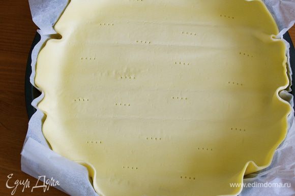 Слоеное тесто выложить вместе с пекарской бумагой в форму для выпечки. Оставить свободный край. Наколоть тесто вилкой.
