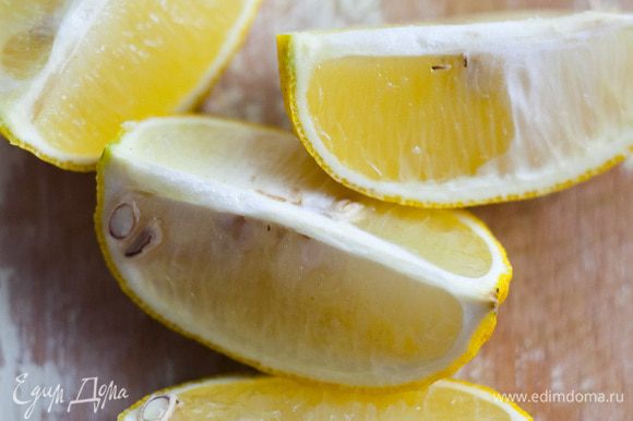 Лимон разрезать на 4 части и вложить внутрь курицы. Противень смазать частью растительного масла и уложить в него курицу.