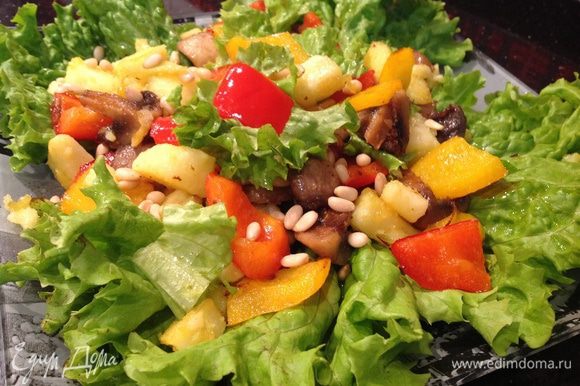 На листья салата выложите овощи, посолите, поперчите по вкусу, сверху посыпьте кедровыми орешками.