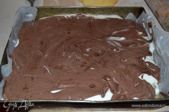 Далее на яблочный слой выкладываем белое тесто, на него аккуратно тесто с какао. Чтобы получить подобие волн, протыкаем в нескольких местах шоколадное тесто вилкой и немного встряхиваем форму с пирогом.