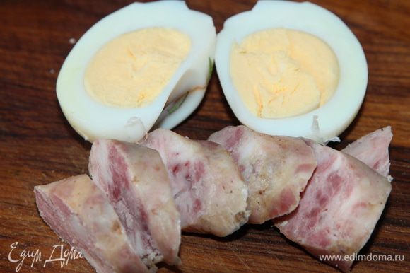 На каждую порцию нарезаем домашние колбаски и кладем по половинке вареного яйца.