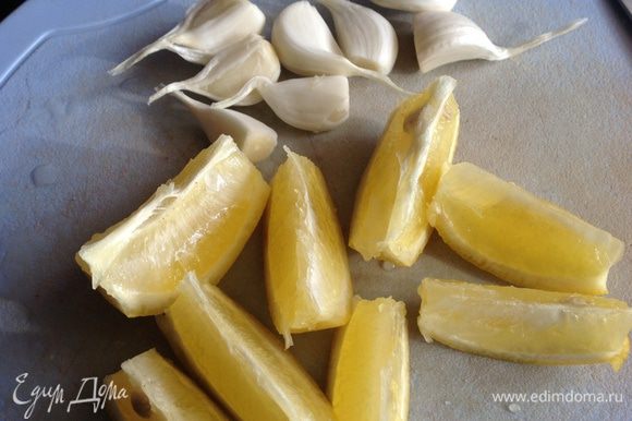 Лимон обдать горячей водой, разрезать на 8 частей. Чеснок разобрать на зубчики не очищая.