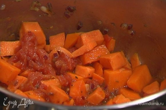 Выложить в кастрюлю с луком батат и тыкву, перемешать, добавить помидоры в собственном соку и еще раз все перемешать.