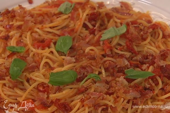 Спагетти с соусом выложить в большую тарелку, посыпать измельченным беконом и листьями базилика.