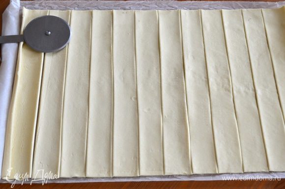 Готовое слоеное тесто развернуть и нарезать полосками шириной 2,5 см.
