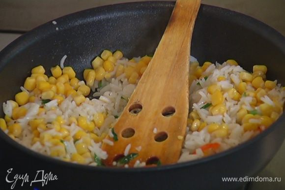 Добавить к луку с чили готовый рис, посолить, поперчить и обжарить, затем добавить кукурузу, все перемешать.