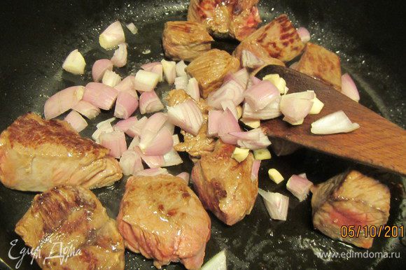 Лук и чеснок измельчаем, добавляем к мясу и готовим 4 минуты.