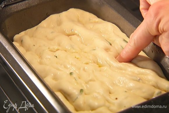Прямоугольную форму для выпечки смазать оставшимся оливковым маслом, выложить тесто, обмять пальцами и вернуть в духовку на 15 минут для расстойки.