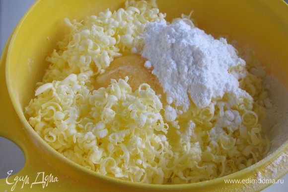 Для теста муку просеять в миску. Туда же натереть сливочное масло на крупной терке, добавить яйцо, сахарную пудру, соль.