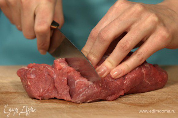 Нарезаем мясо поперек волокон, так наше блюдо получится нежным. Выкладываем нарезанную говядину в форму для запекания.