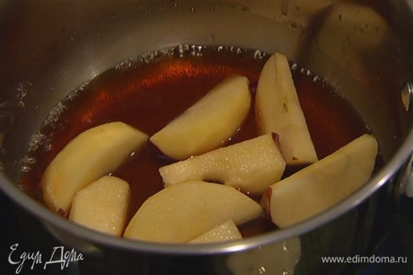 Оставшийся сахар всыпать в небольшую кастрюлю, влить 3 ст. ложки воды, добавить дольки яблок и закарамелизировать их.