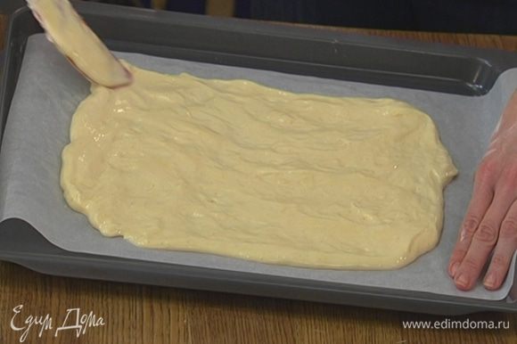 Противень выстелить бумагой для выпечки, смазать ее сливочным маслом, равномерно выложить тесто, так чтобы получился прямоугольник, и отправить в разогретую духовку на 6–7 минут.