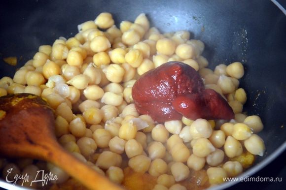 После этого в сковороду добавляем отваренный нут, томатную пасту, добавляем бульон (или воду), перемешиваем.