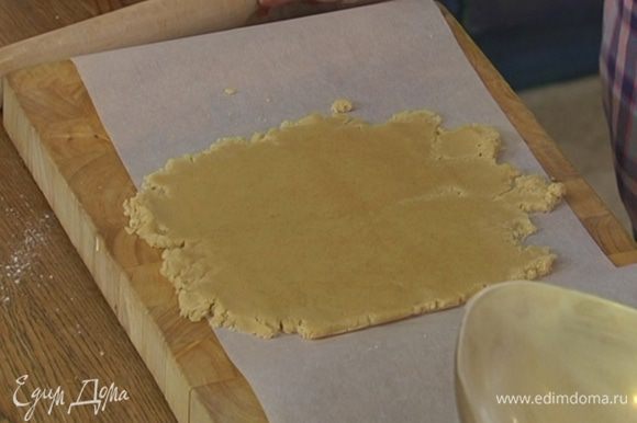Рабочую поверхность выстелить бумагой для выпечки, выложить тесто, накрыть еще одним слоем бумаги и раскатать в пласт.