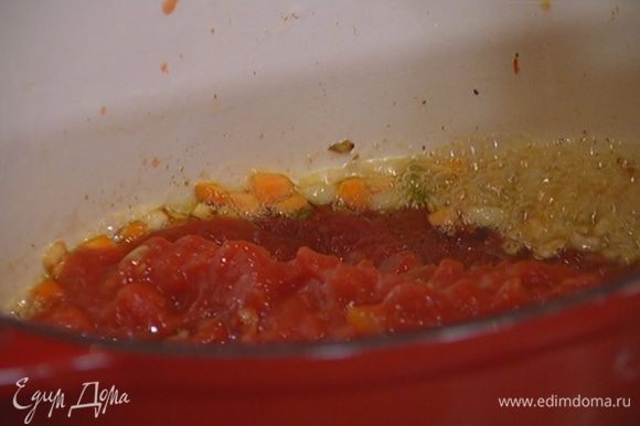 Когда лук станет золотистым, добавить помидоры в собственном соку, томатную пасту и молотый перец чили, все перемешать и прогревать пару минут.