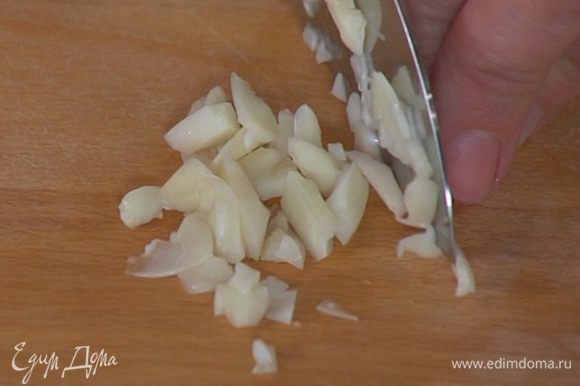 Чеснок почистить, раздавить, мелко порезать и добавить к луку с картофелем.