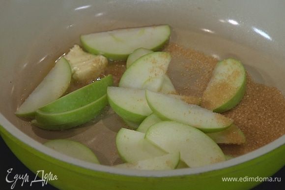 Разогреть в сковороде сливочное масло, всыпать оставшийся сахар и выложить дольки яблока.