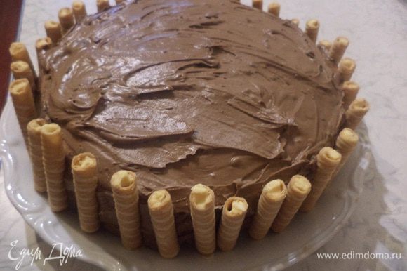 Верх торта посыпать порошком какао. Вафельно-ореховые рулетики разломать пополам и украсить ими бока торта.