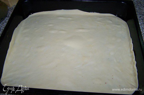 Тесто раскатываем очень тонко, так, чтобы можно было им укрыть противень. Смазываем тесто соусом, не доходя до краёв по 3-4 см.