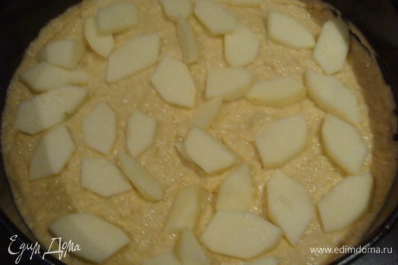 Дно формы застелить бумагой для выпечки, смазать растительным маслом. Яблоко очистить и нарезать на небольшие кусочки. Часть теста выложить в форму, затем выложить кусочки яблок. На начинку равномерно уложить оставшееся тесто.