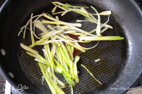 В сковороде нагреть 2 ст.л. оливкового масла и добавить нарезанный полосочками зеленый лук. Обжаривать минуту, помешивая, чтобы лук не пригорел.