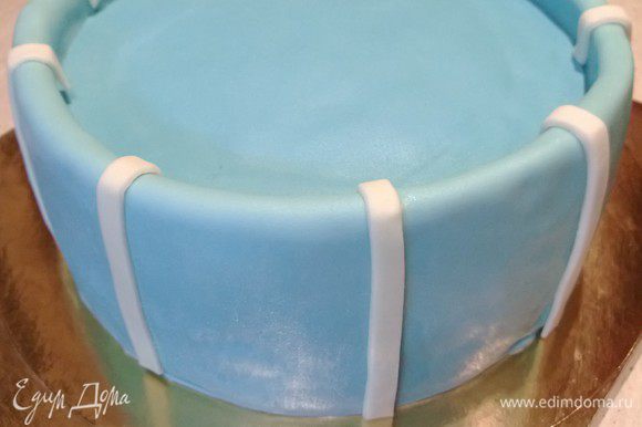 Покрыть торт голубой мастикой. Вырезать и добавить белые полосы из мастики по периметру.
