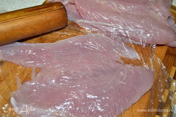 Филе индейки (можно взять куриное) накрываем пищевой пленкой и скалкой раскатываем, получается тонкий пласт мяса.