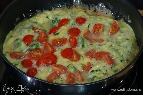 Посыпать омлет оставшимся российским сыром, выложить порезанные помидоры, накрыть сковороду крышкой и готовить еще 2–3 минуты.