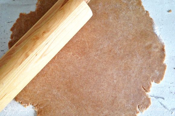На слегка присыпанной мукой поверхности раскатываем тесто в круг, затем перекладываем его на коврик для выпечки или на пергамент.