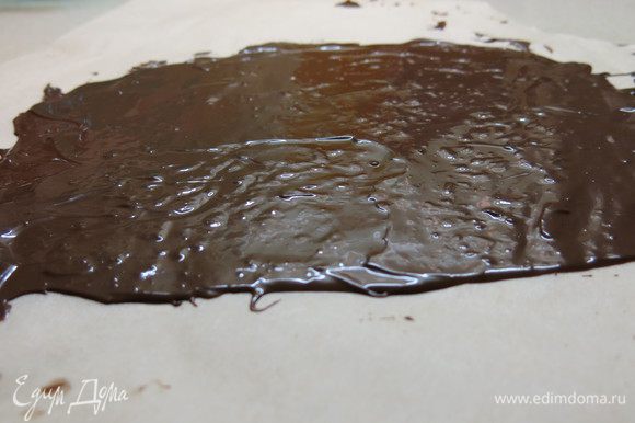 Перекладываем растопленный шоколад на пекарскую бумагу и длинным ножом расправляем в тонкий (2 мм) слой. В форме прямоугольника, приблизительно 28 см на 8 см.