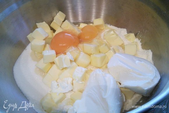 Просеянную муку соедините с разрыхлителем, солью, сахаром. Холодное масло нарубите кубиком и вместе с творогом и средней величины яйцами добавьте к муке.