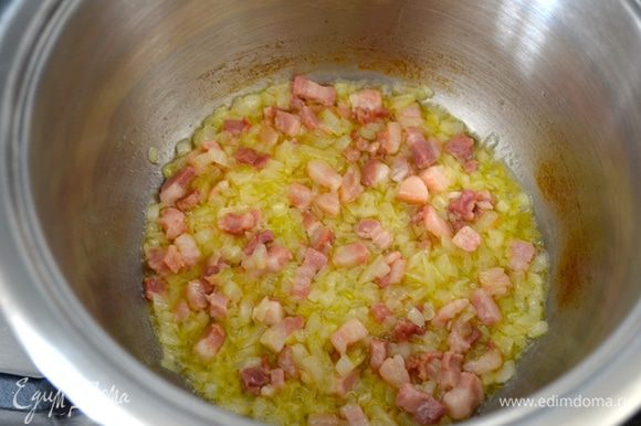 В кастрюле разогрейте сливочное масло и обжарьте на нем минуты 3-4 лук с беконом.