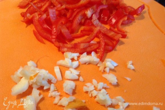 Чеснок мелко порубите, болгарский перец тоже нарежьте соломкой. Добавьте овощи к луку и обжаривайте, помешивая около 4 минут.