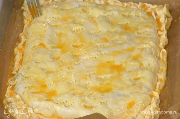 В яичные желтки добавить 1 ч. ложку молока, посолить, перемешать и с помощью кисточки смазать поверхность пирога, затем часто наколоть его вилкой.